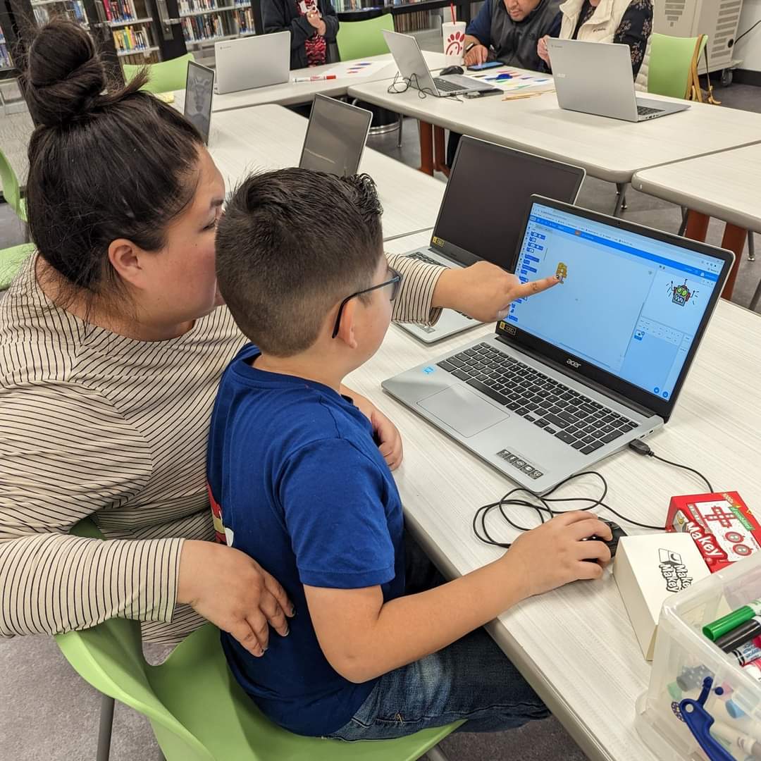 Becky helping a child with a coding activity on a laptop