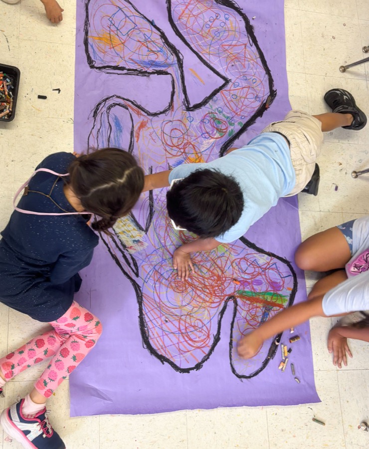 Children creating a chalk pastel body-outline mural