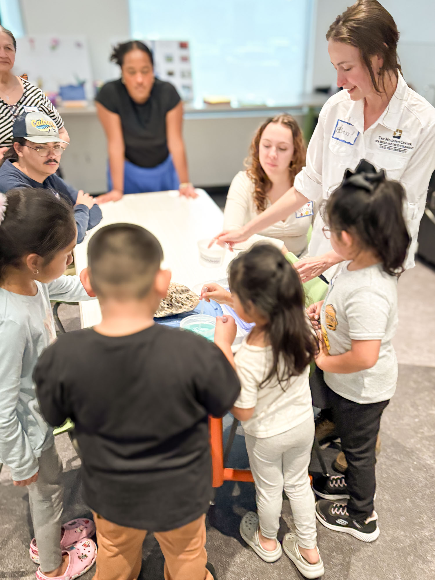 Bess helping children at a One Water family workshop table