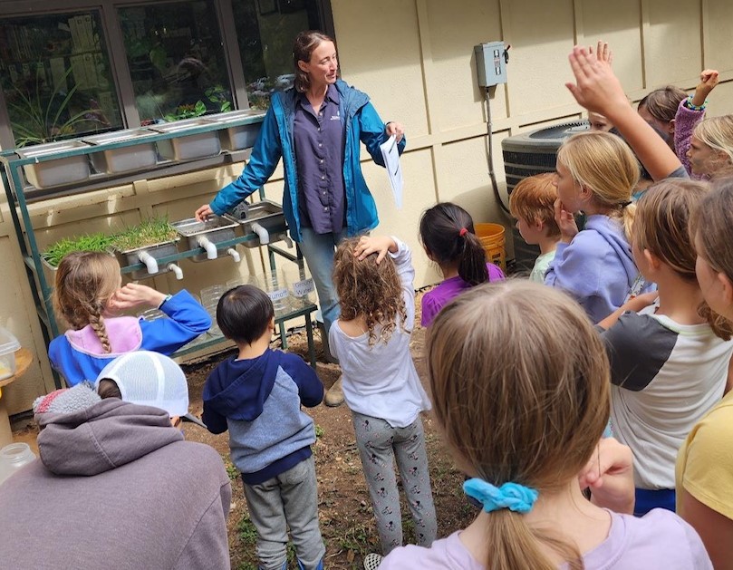 Bess leading an outdoor science lesson with a group of children
