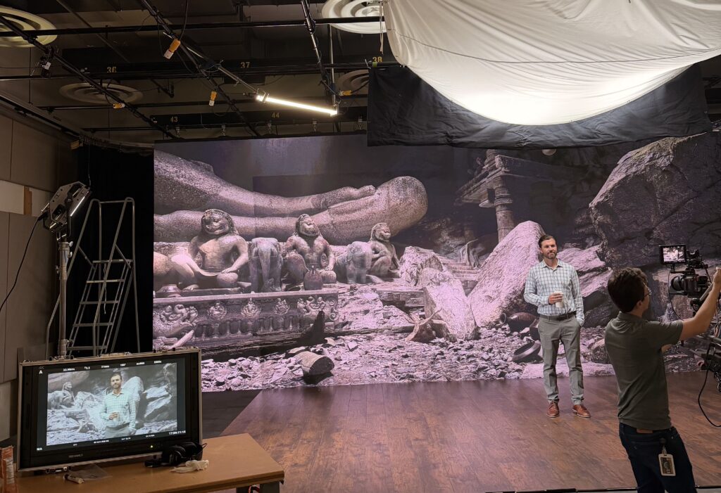 Andrew Rechnitz standing before a large green screen on the sound stage at Alkek One
