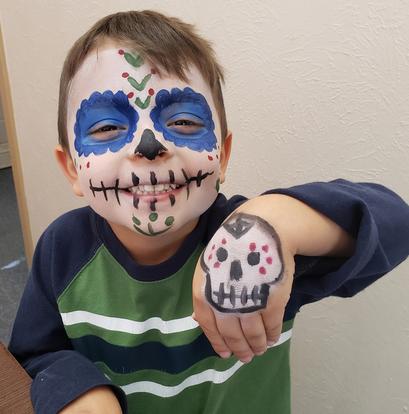 A child with sugar-skull face paint for a Día de los Muertos activity